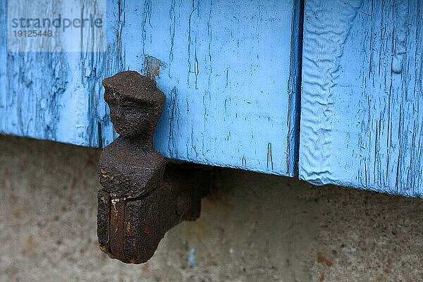 Historische Halterung in Form eines Männchens an einem hellblau gestrichenen Fensterladen