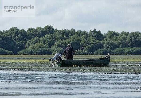 Fischer im Boot auf dem Wasser des Lacul Isaccel  einem See im Donau-Delta. UNESCO Biosphärenreservat Donaudelta. Munghiol  Tulcea  Rumänien  Südosteuropa  Europa