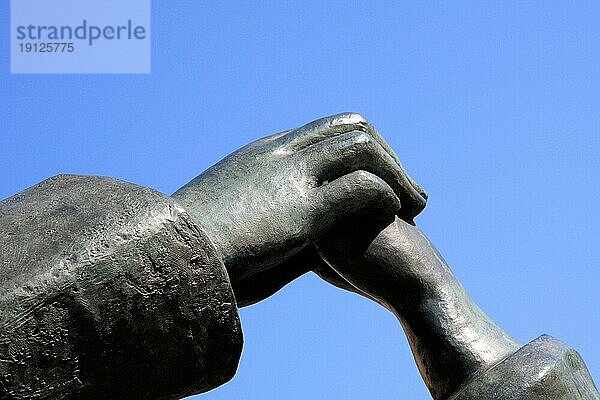 Ausschnitt einer Bronze-Skulptur  männliche und weibliche Hand verbunden  Hintergrund blaür Himmel