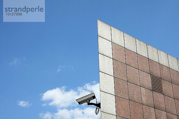 Teil eines Gebäudekomplexes  an dem eine Überwachungskamera installiert ist  Hintergrund blaür Himmel