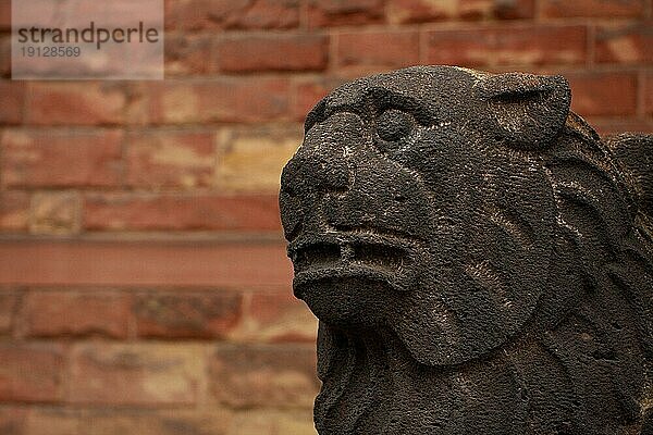 Graue Löwenfigur an einer Kirche  Hintergrund Wand aus Sandsteinplatten