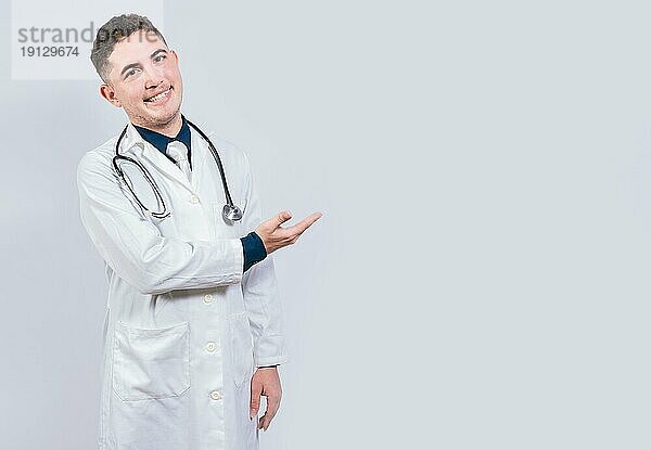 Lateinischer Arzt zeigt eine Anzeige mit Handflächen. Junger Arzt präsentiert etwas mit Handflächen isoliert. Fröhlicher Arzt zeigt etwas
