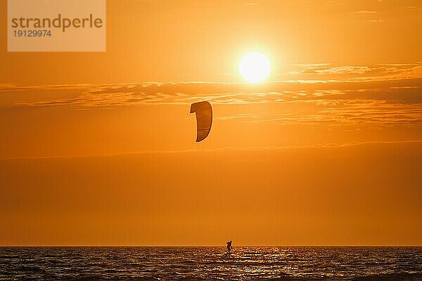 Foiling kiteboarding kitesurfing kiteboarder (kitesurfer) silhouette im Atlantik bei Sonnenuntergang. Strand Fonte da Telha  Costa da Caparica  Portugal  Europa