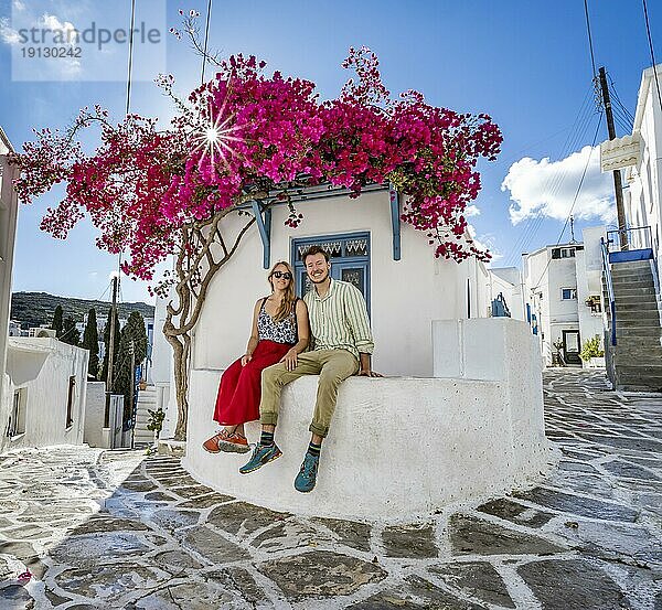Junges verliebtes Paar  weißes kykladisches Haus mit blauer Tür und rosa Bougainvillea  mit Sonnenstern  malerische Gassen des Ortes Lefkes  Paros  Kykladen  Griechenland  Europa