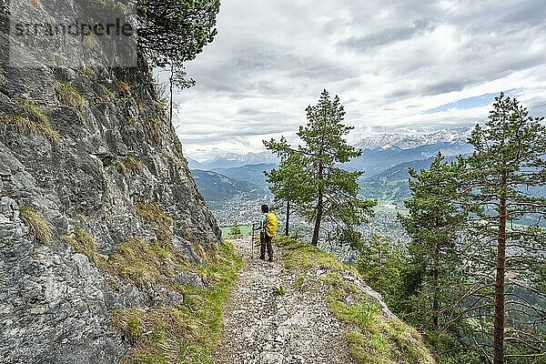 Bergsteigerin beim Aufstieg zum Katzenkopf  Ausblick über den Ort Garmisch-Partenkirchen mit wolkenverhangenen Bergen  Ammergauer Alpen  Bayern  Deutschland  Europa