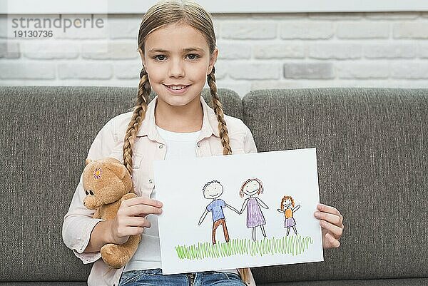 Porträt lächelndes Mädchen auf dem Sofa sitzend  das seine Familie beim Zeichnen von Papier zeigt