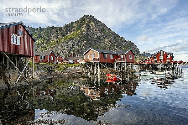 Traditionelle rote Rorbuer Holzhütten  auf Stelzen am Ufer  spiegeln sich im Wasser  Fischerdorf Å i Lofoten  Lofoten  Nordland  Norwegen  Europa