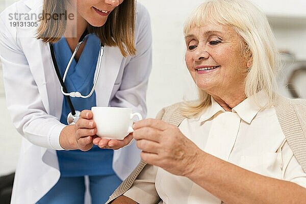 Krankenschwester gibt Tee alte Frau Großaufnahme