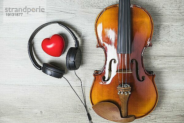 Erhöhte Ansicht rotes Herz mit Kopfhörer umgeben hölzerne klassische Gitarre grau Tabelle