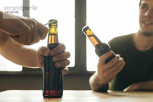 Mann sucht Person  die eine braune Bierflasche öffnet Restaurant