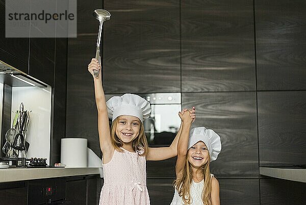 Zwei glückliche Schwestern tragen Kochmütze Küche halten ihre Hände