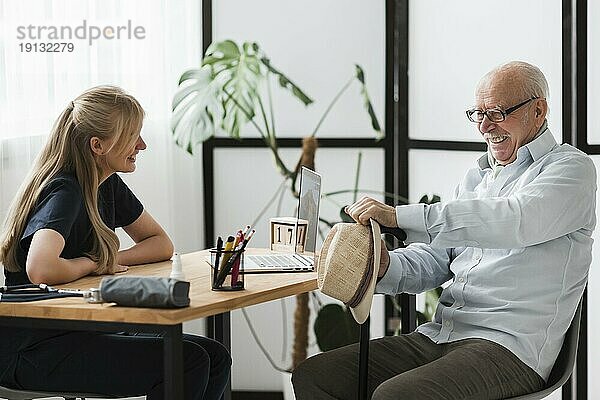 Lächelnder älterer Mann im Pflegeheim mit Krankenschwester