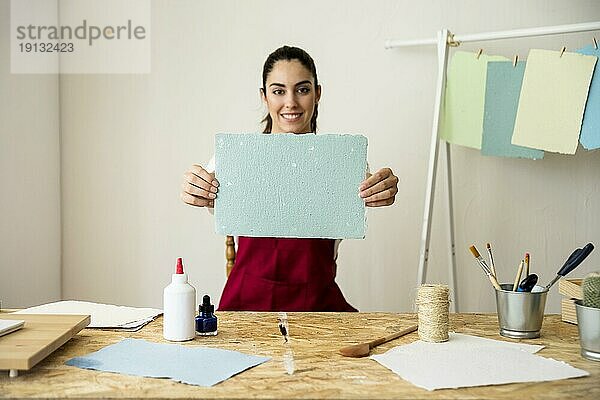 Lächelnde Frau hält handgeschöpftes blaues Papier