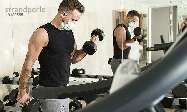 Mann trainiert im Fitnessstudio und trägt eine medizinische Maske