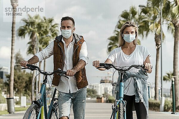 Menschen fahren Fahrrad und tragen medizinische Maske