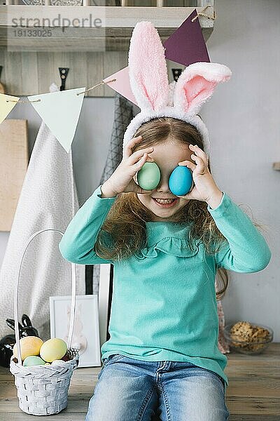 Nettes Mädchen Hasenohren halten farbige Eier Augen