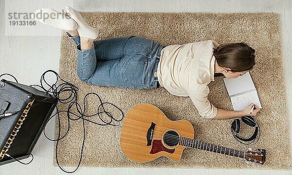 Flat lay weiblichen Musiker zu Hause schriftlich Song mit Kopfhörern akustische Gitarre