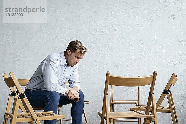 Trauriger Mann Gruppentherapiesitzung mit leeren Stühlen