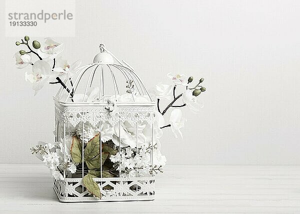 Weißer Vogelkäfig voller Blumen