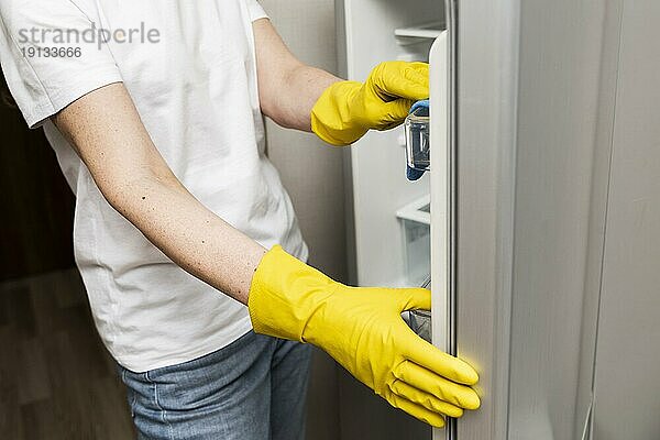 Seitenansicht Frau beim Reinigen des Kühlschranks