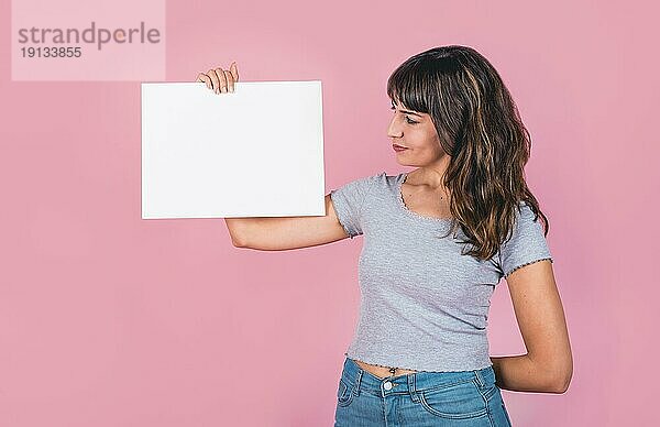 Frau hält ein leeres Schild vor einem rosa Hintergrund