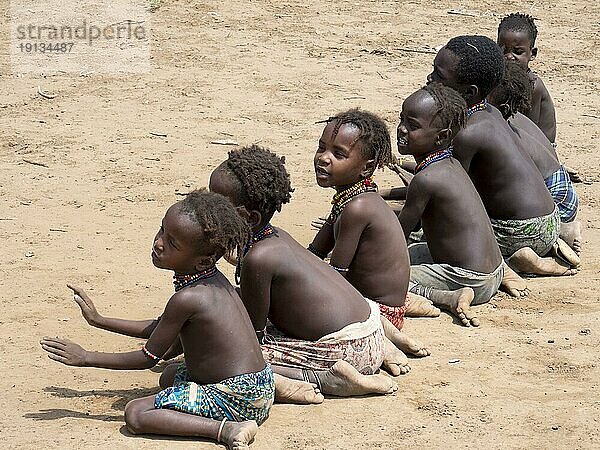 Singende fröhliche Kinder sitzen auf Sandboden  Stamm der Dassanech  Äthiopien  Afrika