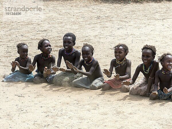 Singende fröhliche Kinder sitzen auf Sandboden  Stamm der Dassanech  Äthiopien  Afrika