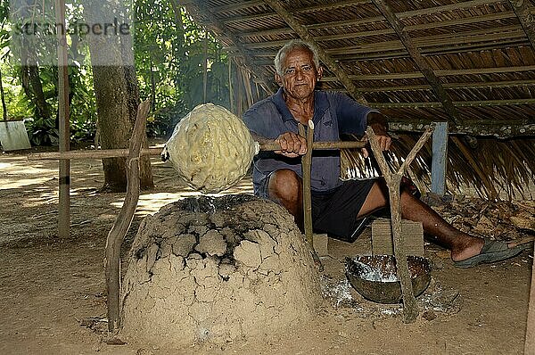 Ein Mann vom Stamm der Caboclos erhitzt einen Gummiball  Bundesstaat Amazonas  Brasilien  Südamerika