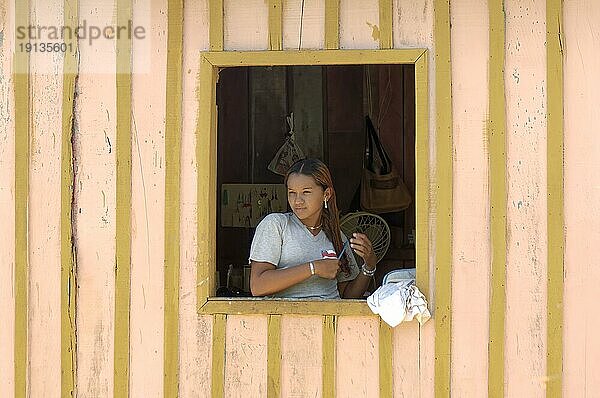 Junge Frau eines Caboclos Stammes beim Kämmen ihrer Haare am Fenster ihres Hauses am Amazonas  Bundesstaat Amazonas  Brasilien  Südamerika