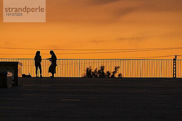 Zwei Frauen auf der Terrasse des Dresdner Kongresszemtrums vor dem sommerlichen Abendhimmel