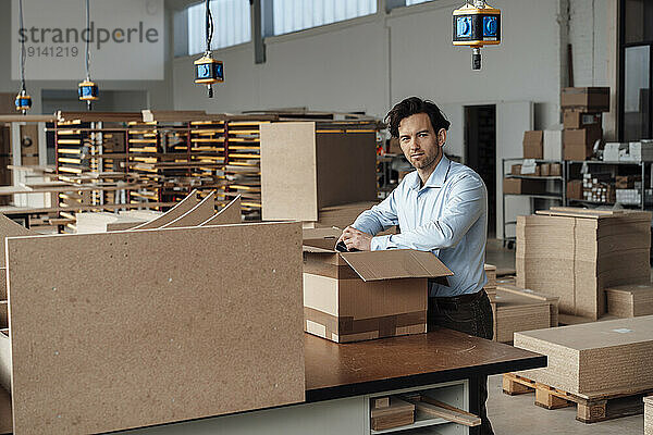 Businessman with cardboard box standing in industry
