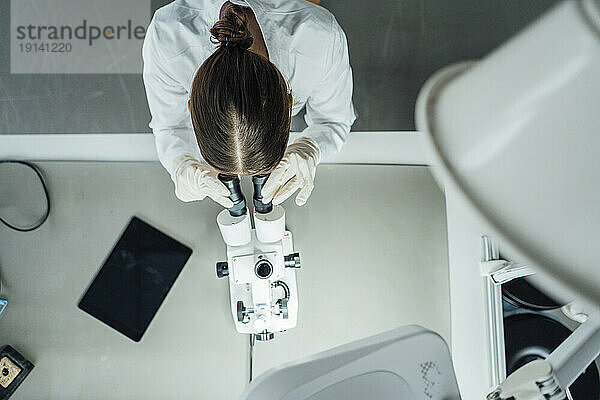 Junger Wissenschaftler arbeitet mit Mikroskop im Labor