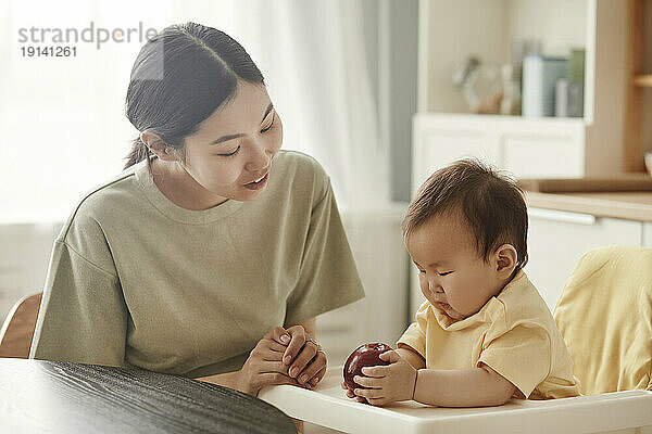 Mutter spricht mit Tochter  die zu Hause einen Apfel hält