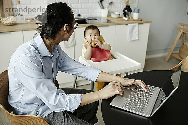Freelancer father looking at daughter sitting at home