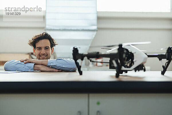 Glücklicher junger Geschäftsmann mit Drohne in der Industrie