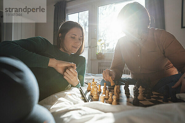 Lesbisches Paar spielt zu Hause Schach im Bett