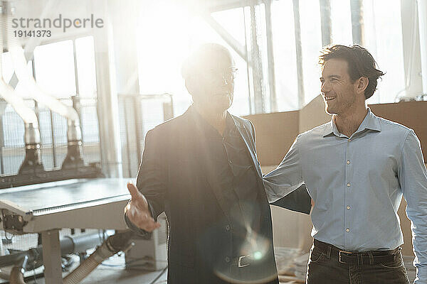 Happy businessman with colleague gesturing in industry