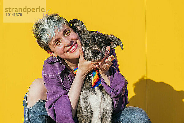 Glückliche lesbische Frau mit Hund vor gelber Wand