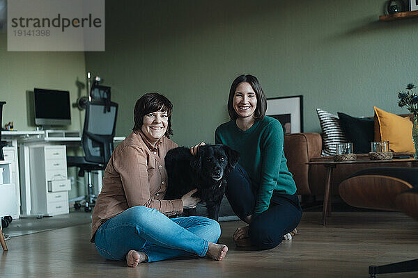 Smiling lesbian couple sitting with dog at home