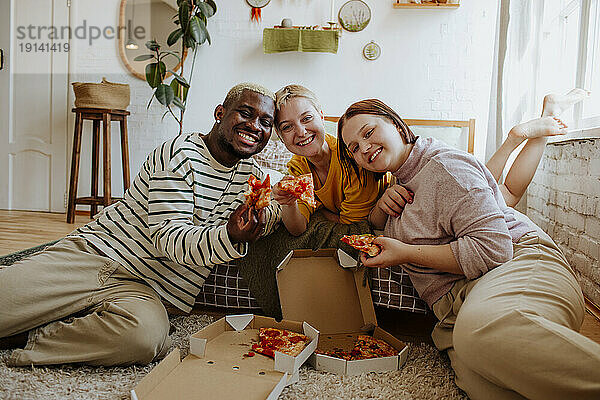 Lächelnde junge Freunde essen Pizza im Bett