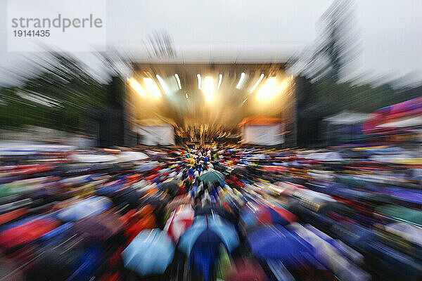 Überfülltes Musikfestival mit Publikum  das Regenschirme trägt