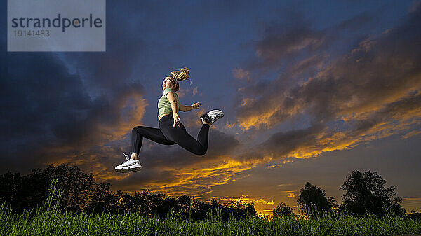 Athlete jumping with sky in background at dusk