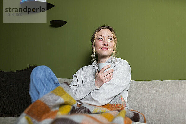 Nachdenkliche Frau mit Tasse entspannt auf der Couch
