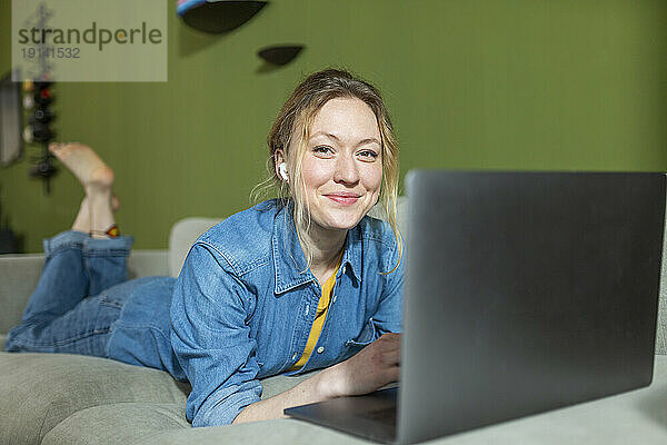 Freiberufler im Jeanshemd arbeitet mit Laptop auf der Couch