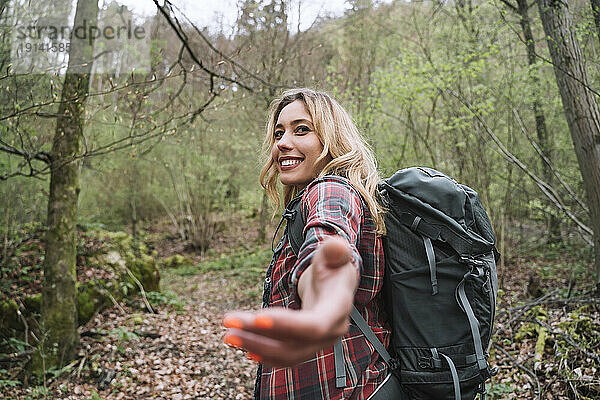 Lächelnder blonder Rucksacktourist beim Wandern im Wald