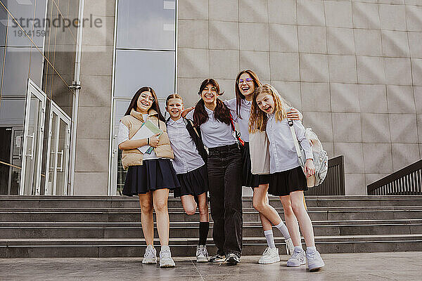 Fröhliche Freunde stehen zusammen vor dem Schulgebäude