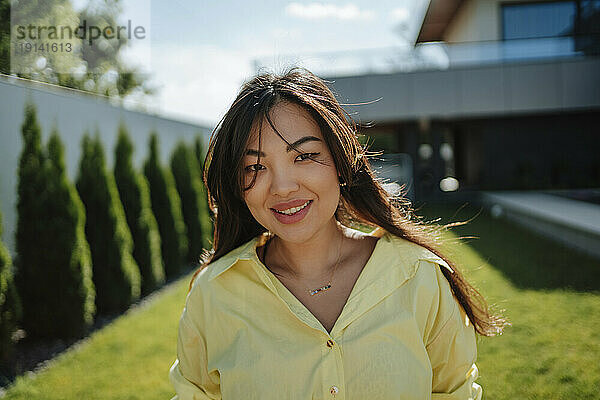 Lächelnde Frau im Hinterhof an einem sonnigen Tag