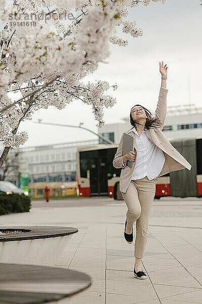 Fröhliche Geschäftsfrau springt am Kirschblütenbaum vorbei