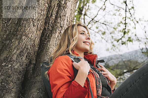 Lächelnde Frau  die sich in der Nähe eines Baumes ausruht