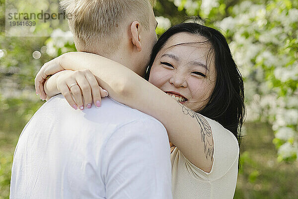 Lächelnde junge Frau umarmt Mann im Park